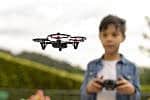 Kid flying drone Concentrated boy flying his toy drone with remote control in his hands in a park. Selective focus